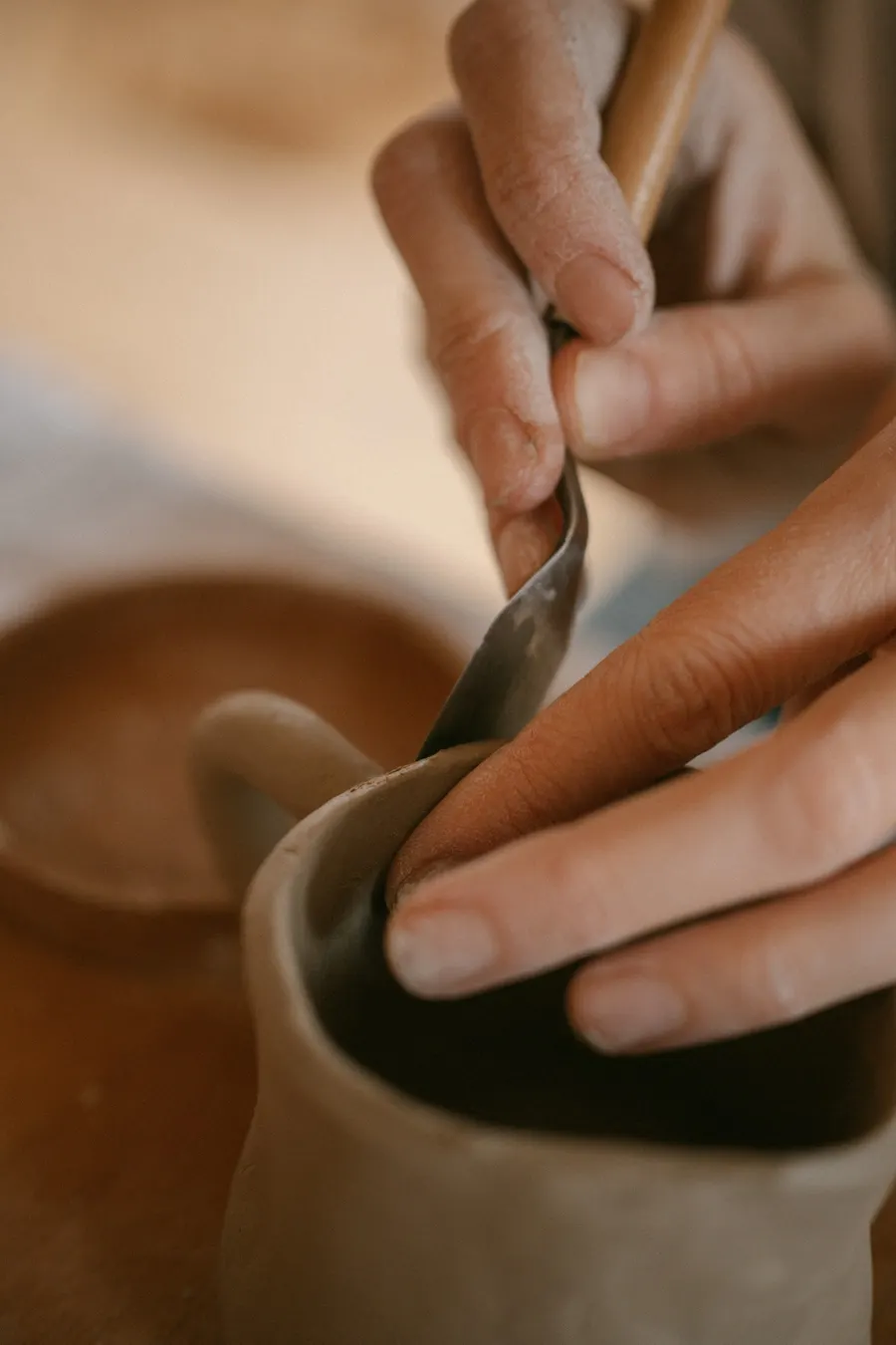 Potter trimming the handle of a clay jug by hand